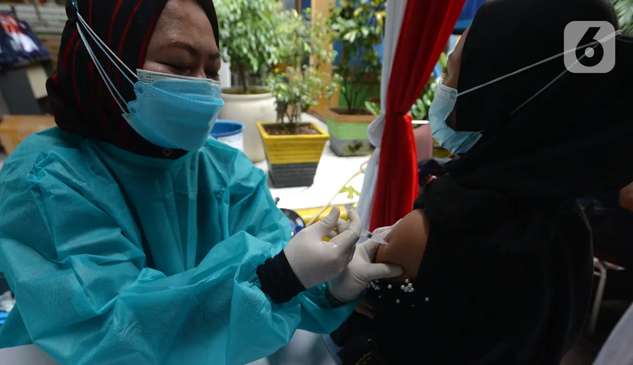 Polisi menyuntikkan vaksin virus corona COVID-19 kepada pedagang Pasar Induk Kramat Jati di Jakarta Timur, Kamis (22/7/2021). Sebanyak 250 pedagang Pasar Induk Kramat Jati menjalani vaksinasi guna menekan penyebaran COVID-19. (merdeka.com/Imam Buhori)