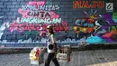 Pengendara motor melintas di depan mural dan gravity di Kolong Tol, Jakarta, Rabu (19/6/2019). Pembuatan Mural Gravity tersebut bermaksud untuk membuat lingkungan sekitar menjadi indah dan elok dipandang mata. (Liputan6.com/Johan Tallo)