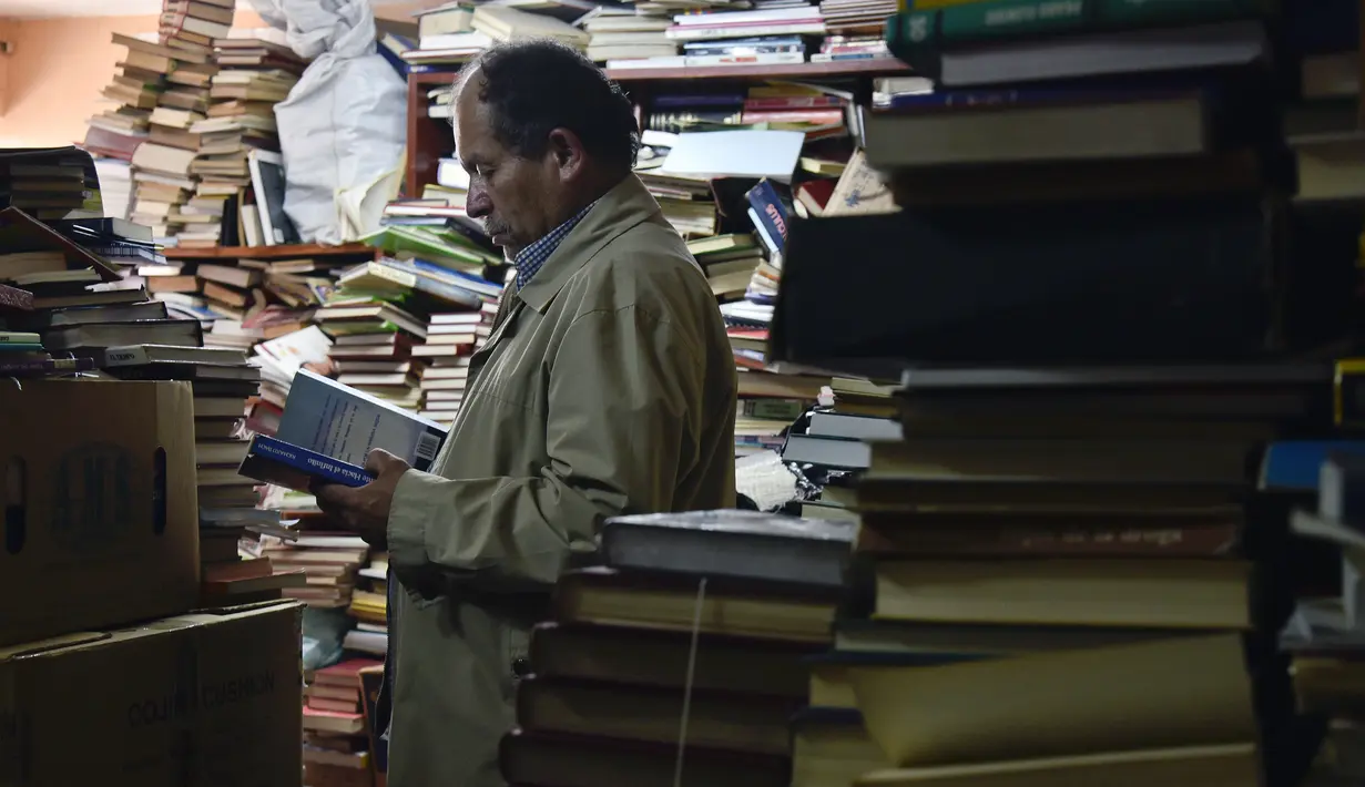 Jose Alberto Gutierrez memeriksa koleksi buku-bukunya di perpustakaan yang ada di lantai satu rumahnya di Bogota, Kolombia, 18 Mei 2017. Pria 54 tahun tersebut telah mengumpulkan buku buangan atau bekas sejak 20 tahun lalu. (GUILLERMO LEGARIA/AFP)