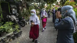Guru menyapa para siswa sebelum mengikuti pembelajaran tatap muka (PTM) di sebuah sekolah di Surabaya, Jawa Timur, Senin (6/9/2021). Pemerintah kembali membuka sekolah di tengah pandemi COVID-19. (JUNI KRISWANTO/AFP)