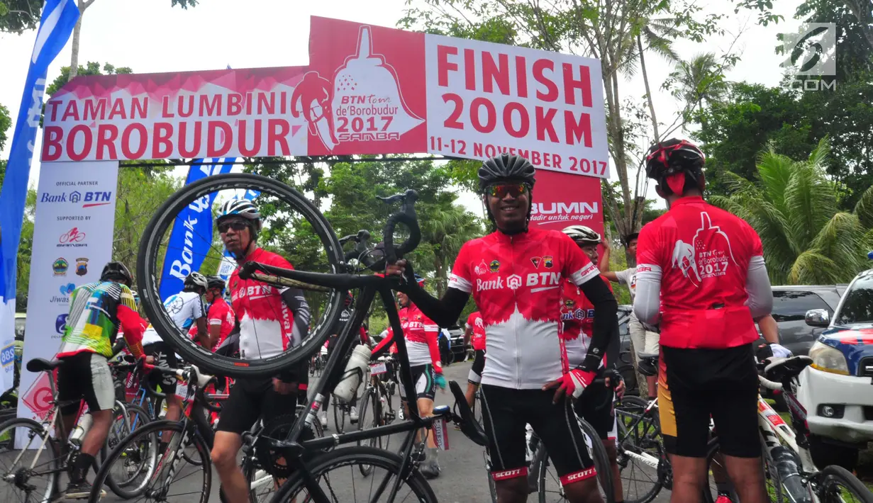 Seorang peserta berpose untuk difoto saat mencapai garis finis dalam BTN Tour de Borobudur XVII di Jawa Tengah (12/11). Perhelatan olahraga sepeda tahunan ini juga diikuti 200 atlet profesional. (Liputan6.com/Gholib)