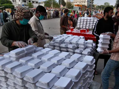 Relawan menyiapkan kotak makanan dan minuman manis tradisional orang-orang berbuka puasa, di Rawalpindi, Pakistan, Minggu, (3/5/2020). Umat Muslim di seluruh dunia sedang melaksanakan Ramadan untuk menahan diri dari makan, minum sejak subuh sampai senja. (AP/Anjum Naveed)