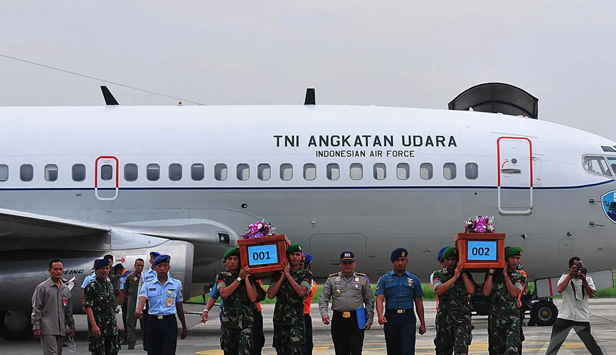 Beberapa petugas mengangkat dua jenazah korban pesawat AirAsia QZ8501 yang sudah berada dalam peti bernomor 001 dan 002 di Lanud TNI AL Juanda, Rabu (31/12/2014). (Liputan6.com/Johan Tallo)