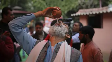 Seorang pria Hindu India minum urin sapi selama acara kelompok agama Hindu untuk mempromosikan konsumsi urin sapi sebagai obat virus corona Covid-19 di New Delhi, India, Sabtu, (14/3/2020). Sekitar 200 orang menghadiri acara minum urin sapi tersebut. (AP Photo/Altaf Qadri)