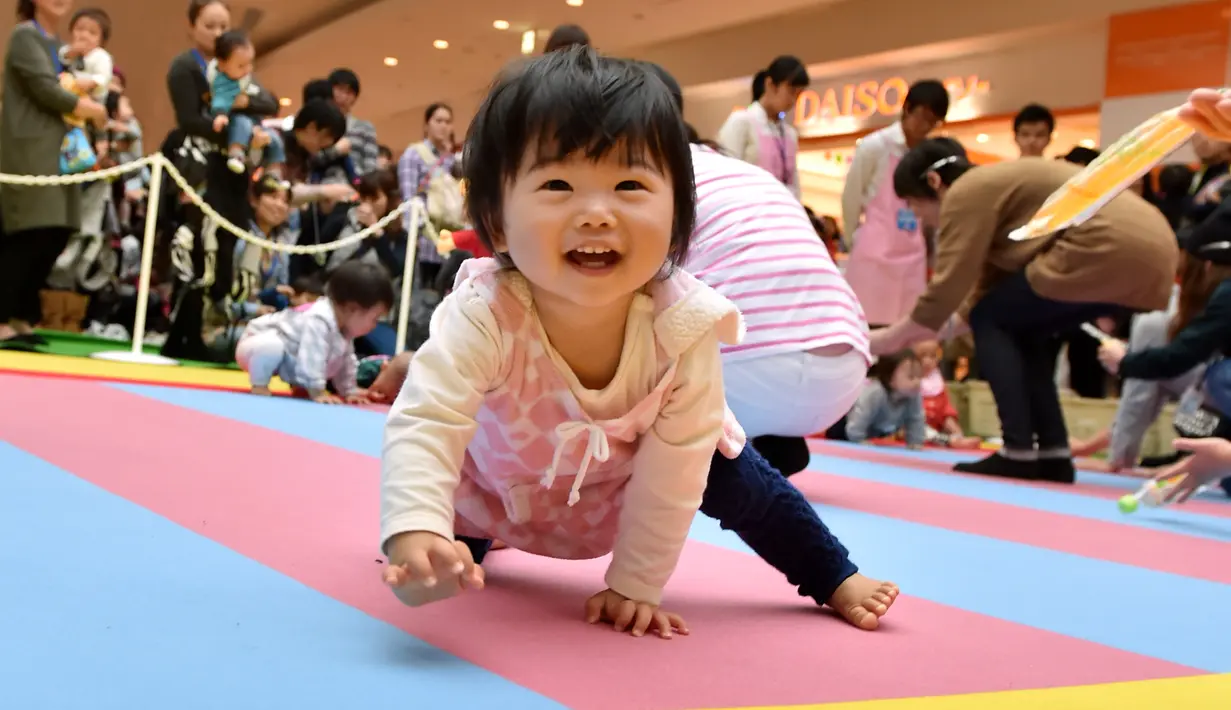 Seorang bayi tersenyum dan ingin menghampiri ibunya saat kompetisi 'Bayi Merangkak',  Yokohama, Jepang, Senin (23/11/2015). Tingkah bayi yang lucu menjadi pemandangan yang menggemaskan bagi para penonton. (AFP Photo/Kazuhiro Nogi)