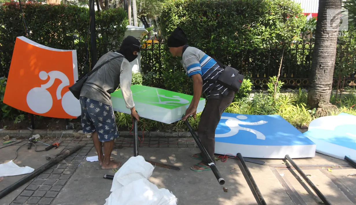 Pekerja memasang neon box Asian Games di depan Balai Kota DKI Jakarta, Jumat (6/7).Lampu neon box berwarna warni yang dipasang menggambarkan berbagai cabang olahraga yang akan dipertandingkan dalam Asian Games 2018. (Liputan6.com/Arya Manggala)
