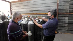 Orang-orang memeriksa tekanan oksigen di tempat pengisian ulang oksigen di Baghdad, Irak (7/7/2020). Pabrik pengisian oksigen milik pemerintah di Irak meningkatkan pengisian tabung oksigen dan gas cairnya untuk memenuhi permintaan rumah sakit di tengah terus bertambahnya infeksi COVID-19. (Xinhua)