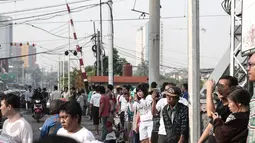 Sejumlah warga berkumpul di lokasi kecelakaan bus TransJakarta yang ditabrak kereta api Senja Utama Solo di perlintasan kereta Mangga Dua, Jakarta, Kamis (19/5). Saat insiden, bus TransJakarta sedang tidak mengangkut penumpang (Liputan6.com/Faizal Fanani)