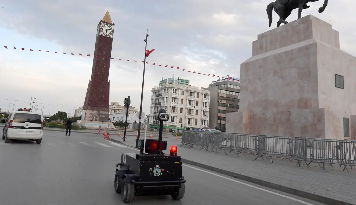 Sebuah robot polisi Tunisia berpatroli selama kebijakan penguncian (lockdown) di sepanjang Avenue Habib Bourguiba, pusat ibu kota Tunis, Rabu (1/4/2020). Robot ini dilengkapi dengan deteksi termal (temperatur tubuh manusia) dan kemampuan video audio secara real time. (FETHI BELAID/AFP)
