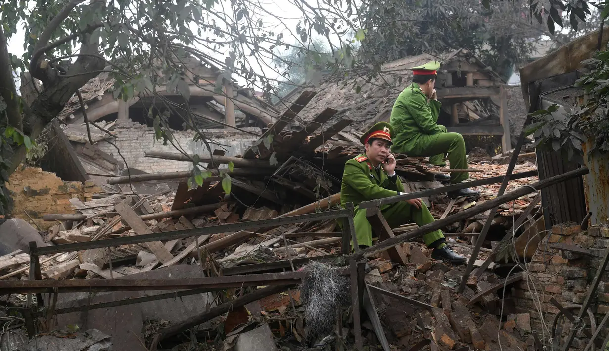 Petugas polisi berjaga di lokasi ledakan di provinsi utara Bac Ninh, Vietnam (3/1). Ledakan tersebut menghancurkan total lima rumah dan memecahkan kaca jendela gedung-gedung sekitarnya. (AFP Photo/Hoang Dinh Nam)
