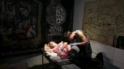 Seorang wanita terbaring saat di tato oleh seniman selama acara Festival Tato Internasional di Sochi, Rusia, (23/4). Sejumlah wanita tampak antusias untuk mentato tubuhnya di festival tato terbesar di negara tersebut. (REUTERS/Kazbek Basayev)