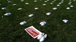 Serikat perawat Amerika Serikat (AS) meletakkan 164 pasang sepatu putih di luar US Capitol di Washington, DC pada Selasa (21/7/2020). Sepatu-sepatu itu melambangkan para perawat yang tewas akibat covid-19 dan menuntut Senat bertindak cepat melindungi perawat di garis depan. (Olivier DOULIERY/AFP)