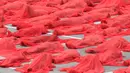 Ratusan orang berpose mengenakan kain merah transparan saat foto bugil massal di atap sebuah supermarket di Melbourne (9/7). Pemotretan ini dilakukan di tengah suhu udara 7 derajat Celsius. (AFP Photo/Paul Crock)