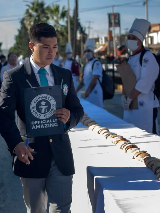 Petugas Guinness World Record menilai kue raja sepanjang 2.063,43 meter, di Saltillo, Negara Bagian Coahuila, Meksiko, 6 Januari 2019. Acara ini juga digelar sebagai pesta tahunan Epiphany di kota tersebut. (Julio Cesar AGUILAR/AFP)
