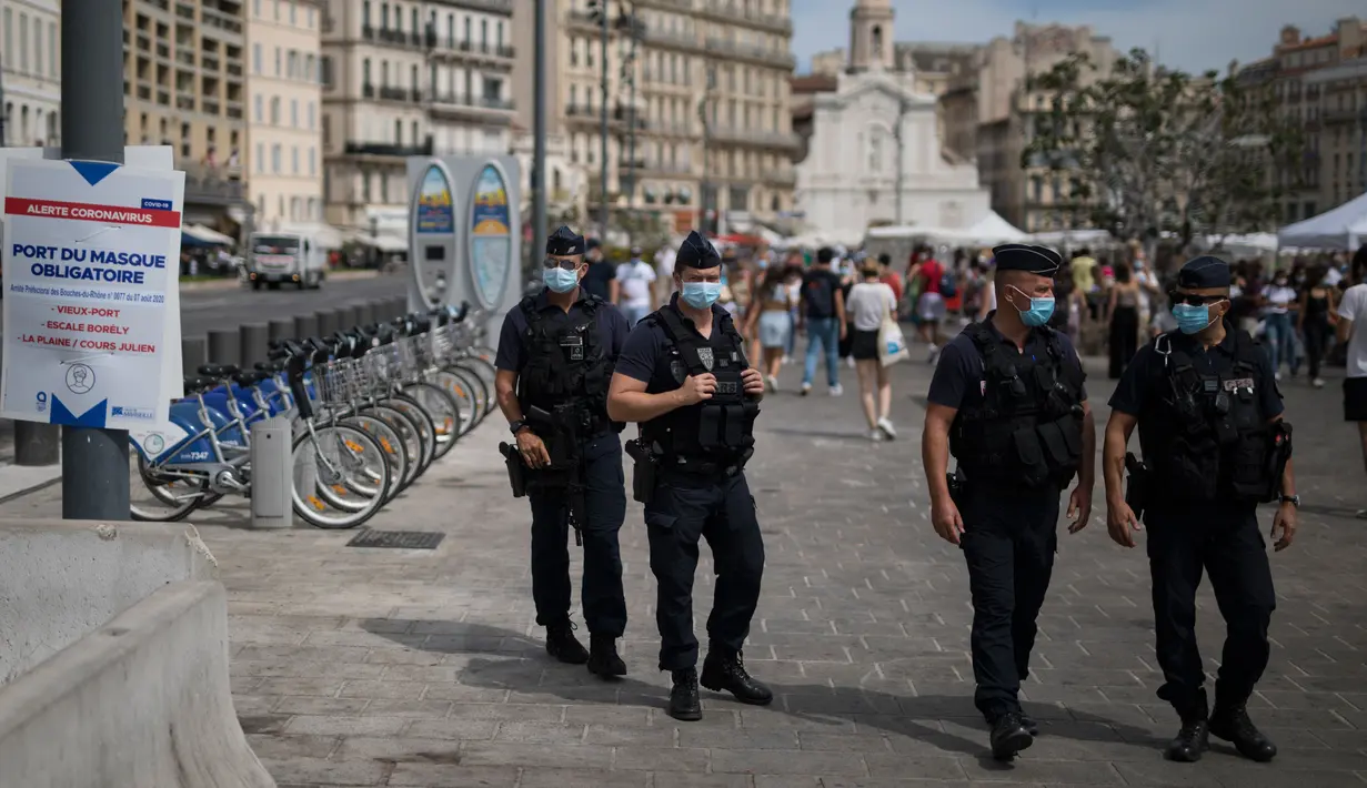 Polisi anti huru-hara Prancis mengamati warga yang mengenakan masker di Marseille, Selasa (18/8/2020). Pemerintah Prancis mengirim polisi anti huru hara ke wilayah Marseille untuk membantu menegakkan peraturan penggunaan masker saat negara itu mencatat lonjakan kasus COVID-19. (AP Photo/Daniel Cole)