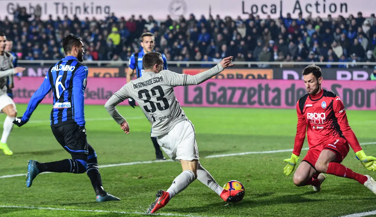 Penyerang Juventus, Federico Bernardeschi (tengah) menendang bola ke arah kiper Atalanta Etrit Berisha (kanan) pada perempat final Coppa Italia 2018-2019 di Stadion Atleti Azzurri d'Italia, Bergamo, Rabu (30/1). (Miguel MEDINA/AFP)