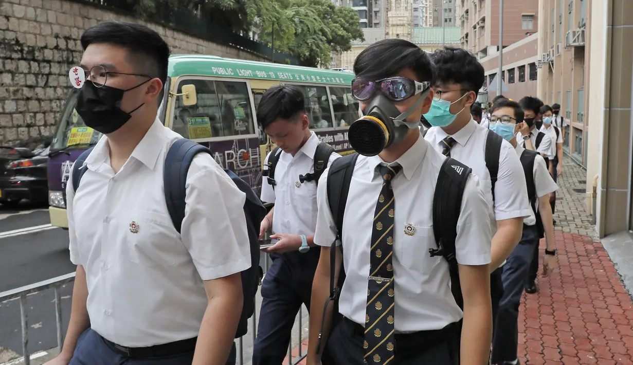 Para siswa sekolah mengenakan topeng dan helm berjalan di luar St. Paul's College selama protes di Hong Kong, Selasa (3/9/2019). Puluhan ribu siswa di Hong Kong mogok sekolah di hari pertama tahun ajaran baru. (AP Photo/Kin Cheung)