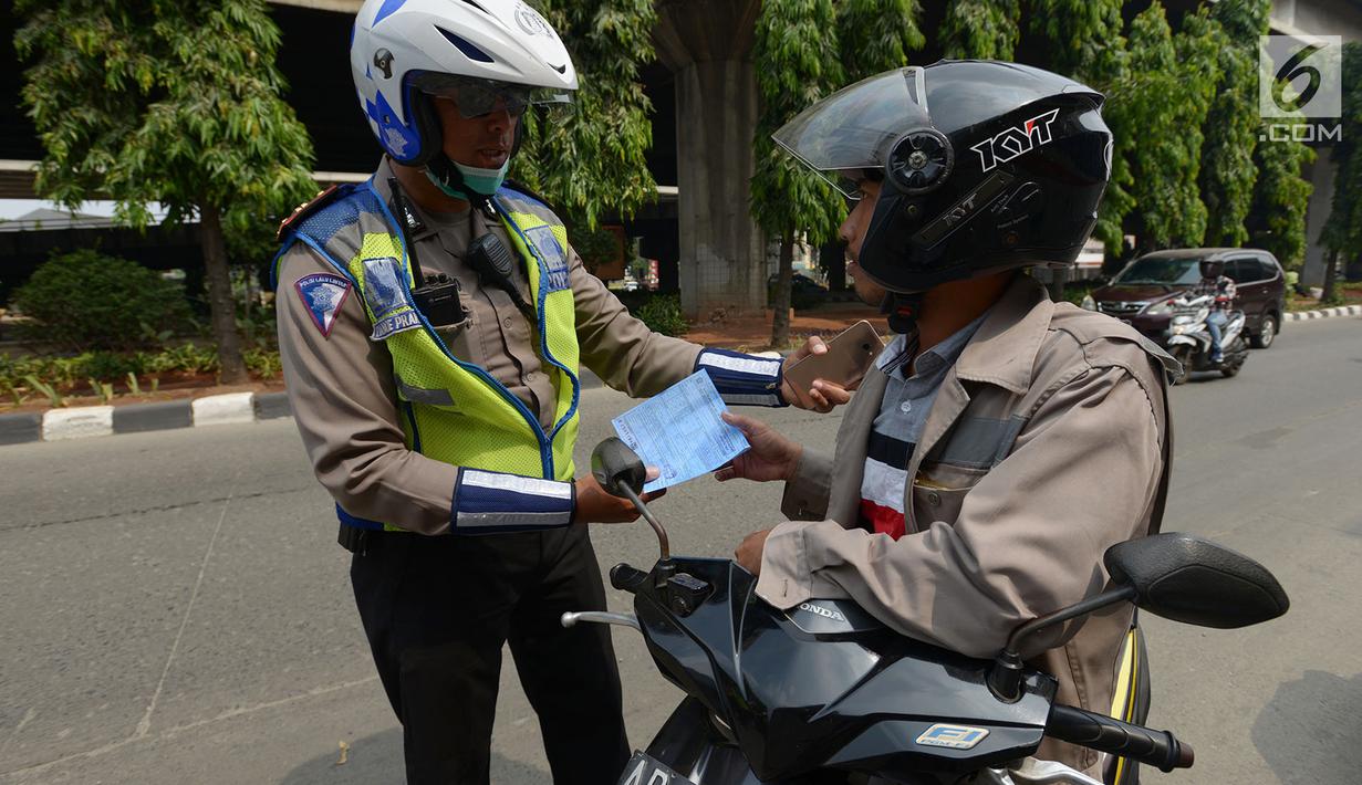Polisi lalu lintas melakukan tilang terhadap pengendara motor saat razia Operasi Patuh Jaya 2019 di kawasan Kebon Nanas, Jakarta, Kamis (29/8/2019). Operasi ini diharapkan dapat meningkatkan kepatuhan dan ketertiban dalam berlalu lintas serta mengurangi angka kecelakaan. (merdeka.com/Imam Buhori)
