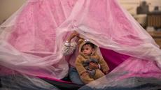 Yasmin menggendong saudara laki-lakinya, Ali, keduanya mengungsi dari pinggiran selatan Beirut, Dahiyeh, mereka berlindung dari hujan di dalam tenda di sepanjang pantai, Beirut, Lebanon, Kamis, 26 Maret 2026. Kondisi pengungsi di Lebanon saat ini berada dalam fase krisis kemanusiaan. (AP Photo/Emilio Morenatti)