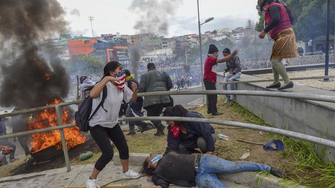 Seorang pengunjuk rasa terbaring di tanah ketika demonstran dibubarkan dari gedung parlemen oleh polisi anti huru hara di Quito (8/10/2019). Para demonstran memprotes terhadap keputusan Presiden Ekuador Lenin Moreno yang mencabut subsidi bahan bakar. (AFP Photo/Martin Bernetti)
