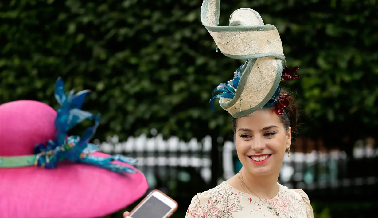 Racegoers dengan hiasan kepala tiba pada hari pertama ajang pacuan kuda Royal Ascot di Inggris, Selasa (19/6). Seperti biasanya, topi-topi cantik dan unik menjadi properti wajib bagi para bangsawan wanita yang hadir. (AP/Tim Ireland)