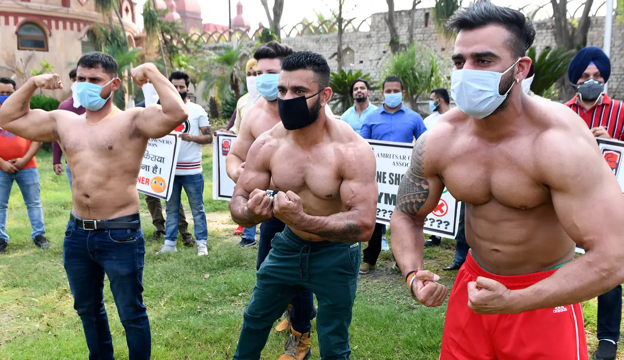 Pemilik dan pelatih gym memamerkan otot mereka saat protes menuntut pemerintah membuka kembali pusat kebugaran di Amritsar, India, Minggu (7/6/2020). Mereka meminta aktivitas tempat olahraga gym juga diizinkan buka setelah pelonggaran lockdown, bukan hanya kegiatan perekonomian. (NARINDER NANU/AFP)
