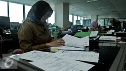 Seorang PNS saat membaca dokumen di kantor Balai Kota DKI, Jakarta, Rabu (22/7/2015). Hari ini adalah hari pertama masuk kerja di lingkungan Pemerintah Daerah Jakarta pasca cuti bersama Idul Fitri 1436H. (Liputan6.com/Johan Tallo)