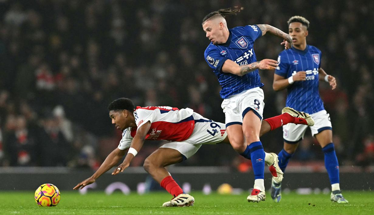 Pemain Arsenal, Myles Lewis-Skelly (kiri) berebut bola dengan pemain Ipswich Town, Kalvin Phillips pada laga lanjutan Liga Inggris 2024/2025 di Emirates Stadium, London, Inggris, Sabtu (28/12/2024) WIB. (AFP/Glyn Kirk)