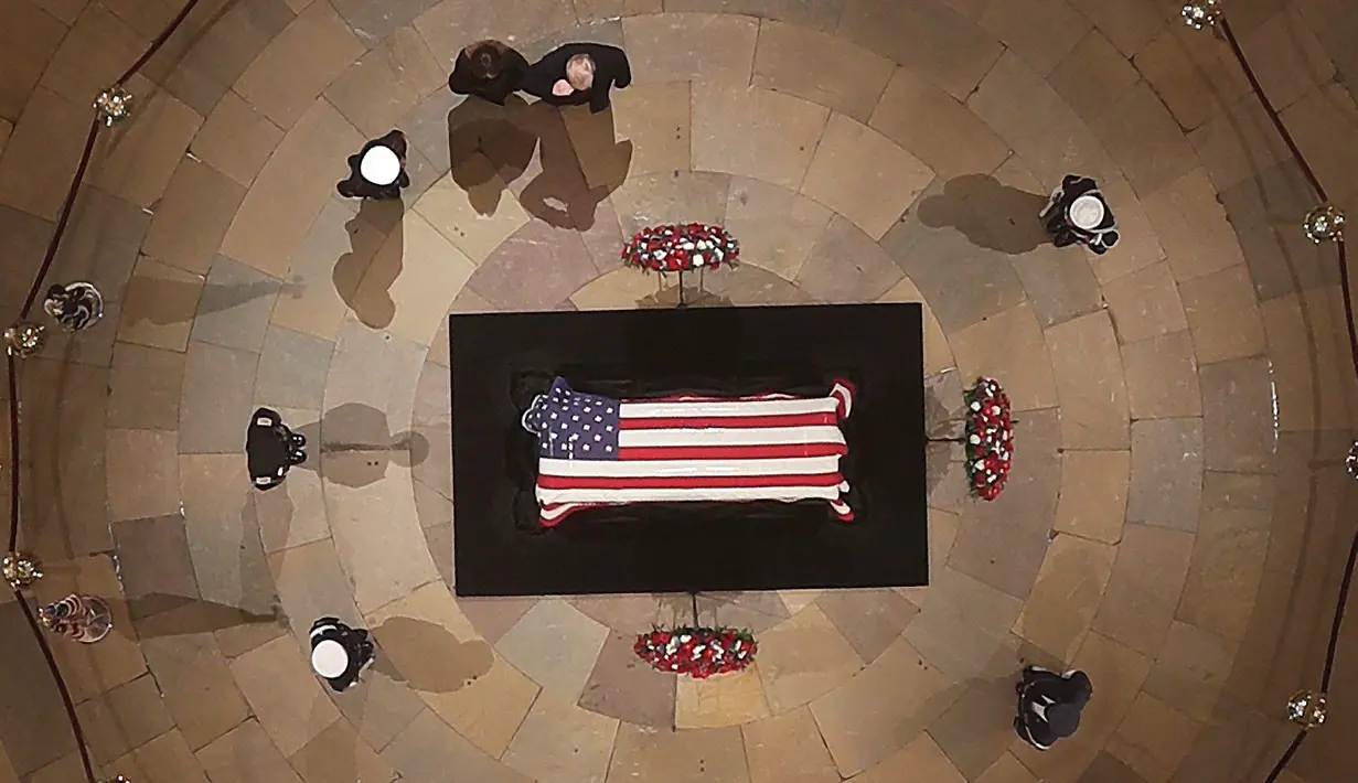 Presiden Amerika Serikat, Donald Trump dan First Lady, Melania Trump memberikan penghormatan terakhir di depan peti jenazah George HW Bush di Gedung Capitol, Washington, Senin (3/12). (Pool photo by Morry Gash via AP)