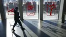 Seorang pekerja berjalan melewati jendela yang didekorasi dengan gambar olahraga musim dingin di Desa Olimpiade Musim Dingin, Beijing, China, Jumat, 24 Desember 2021. Olimpiade dan Paralimpiade Musim Dingin 2022 akan diadakan mulai bulan Februari. (AP Photo/Mark Schiefelbein)
