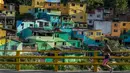 Seorang wanita berolahraga sambil menyusuri kawasan kumuh El Pesebre di pinggiran kota Medellin, Kolombia, 19 Juni 2017. Seniman Prancis, Tarik Bouanani melukis 230 rumah di kawasan tersebut membentuk mural raksasa. (JOAQUIN SARMIENTO/AFP)