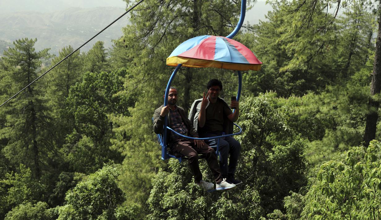 <p>Wisatawan menikmati naik kursi gantung di kota resor bukit Murree, selama hari pertama Idul Fitri di dekat Islamabad, Pakistan, Selasa, 3 Mei 2022. (AP Photo/Rahmat Gul)</p>