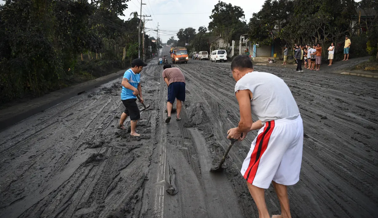 Warga membersihkan jalanan dari abu vulkanik setelah erupsi Gunung Taal di Tagaytay, Provinsi Cavite, Filipina, Senin (13/1/2020). Gunung yang terakhir meletus pada tahun 1977 tersebut melontarkan abu vulkanik mencapai 50.000 kaki (15.000 meter) ke atmosfer. (TED ALJIBE/AFP)