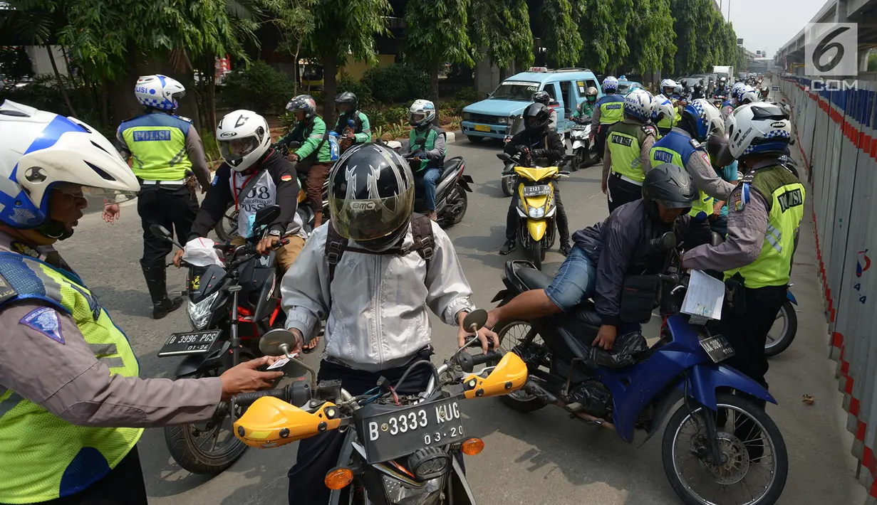 Polisi lalu lintas melakukan tilang terhadap pengendara motor saat razia Operasi Patuh Jaya 2019 di kawasan Kebon Nanas, Jakarta, Kamis (29/8/2019). Operasi ini diharapkan dapat meningkatkan kepatuhan dan ketertiban dalam berlalu lintas serta mengurangi angka kecelakaan. (merdeka.com/Imam Buhori)