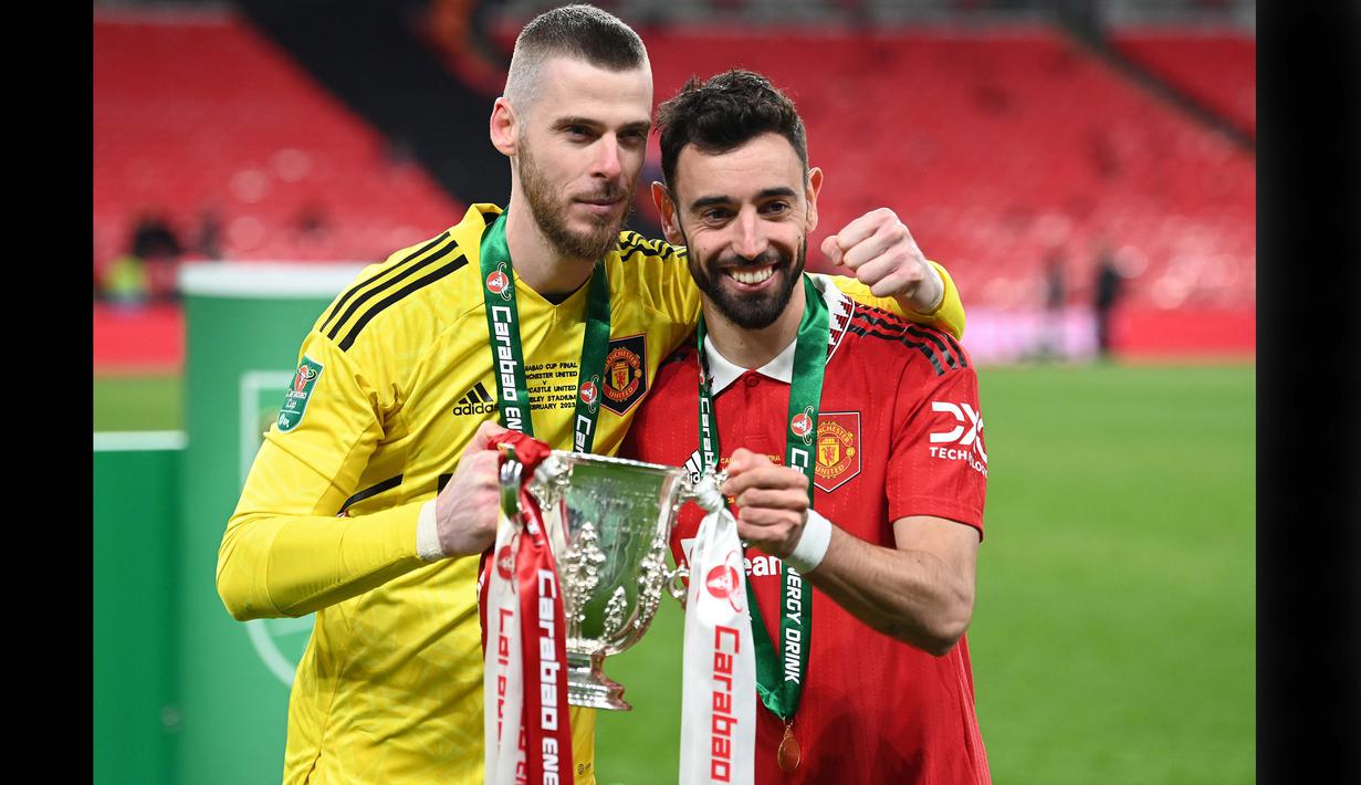 <p>Pemain Manchester United, David De Gea (kiri) dan Bruno Fernandes berpose bersama trofi Carabao Cup 2023 setelah mengalahkan Newcastle United di Wembley Stadium, Minggu (26/2/2023) waktu setempat. (AFP/Glyn Kirk)</p>