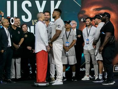 Petinju Inggris Anthony Joshua (tengah kanan) dan petinju Ukraina Oleksandr Usyk (tengah kiri) saling pandang saat penimbangan di King Abdullah Sports City, Jeddah, Arab Saudi, 19 Agustus 2022. Joshua dijadwalkan melawan juara bertahan Usyk dalam pertandingan ulang tinju kelas berat di Jeddah pada 20 Agustus. (AP Photo/Hassan Ammar)