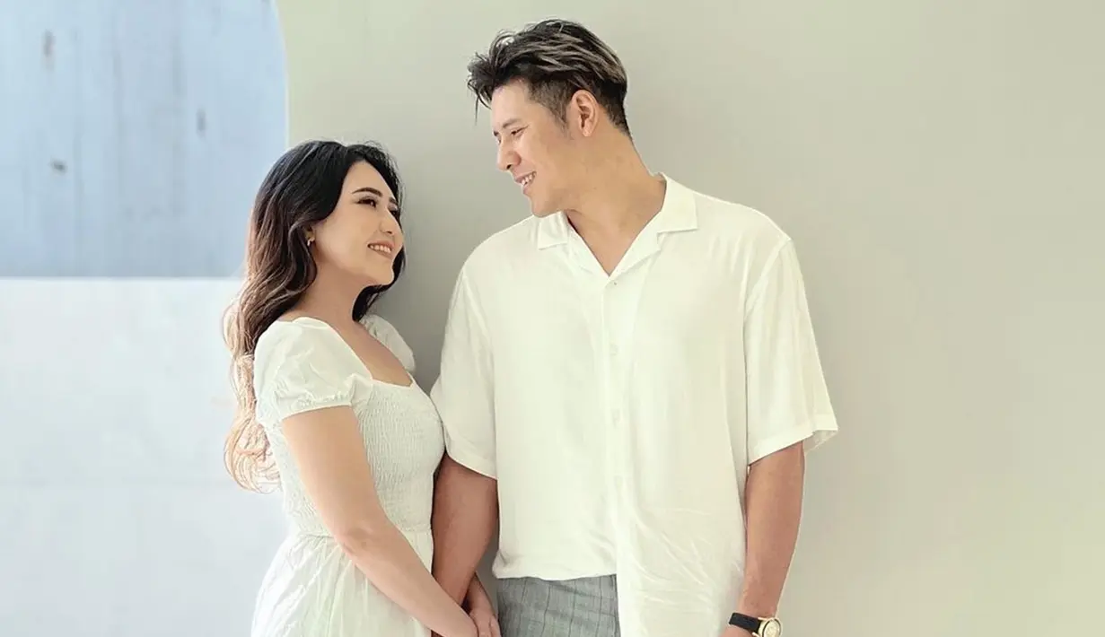 Dengan balutan dress putih, Via tampil menawan dalam pemotretan bareng sang suami. Menyelaraskan penampilan, vokalis band Papinka itu juga memakai warna putih untuk kemejanya. Pasangan pengantin baru ini tersenyum saling bertatapan penuh mesra. (Liputan6.com/IG/@chevra_yo88)
