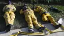Petugas pemadam kebakaran (damkar) beristirahat setelah kelelahan mengatasi kebakaran yang disebut Lilac Fire di Bonsall, California, Jumat (8/12). Lilac Fire telah menyebar dari 10 hektar menjadi 4.100 hektar hanya dalam beberapa jam. (Robyn Beck/AFP)