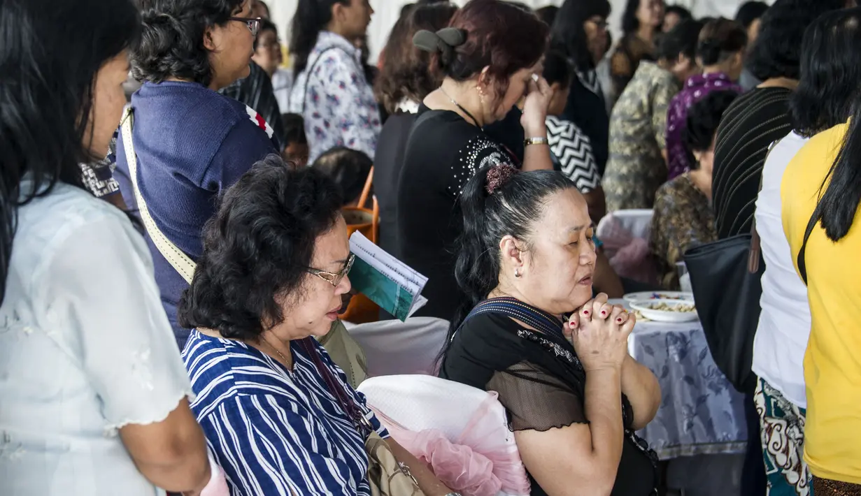 Kerabat berdoa dalam pemakaman Martha Djumani, salah satu korban meninggal dalam serangan di Gereja Pantekosta, Surabaya, Jawa Timur, Senin (14/5). Serangan bom yang melanda tiga gereja di Surabaya menewaskan belasan orang. (AFP PHOTO/JUNI KRISWANTO)