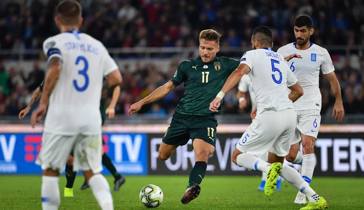 Striker Italia, Ciro Immobile, berusaha melewati bek Yunani, Dimitris Siovas, pada laga Kualifikasi Piala Eropa 2020 di Stadion Olimpico, Roma, Sabtu (12/10). Italia menang 2-1 atas Yunani. (AFP/Alberto Pizzoli)