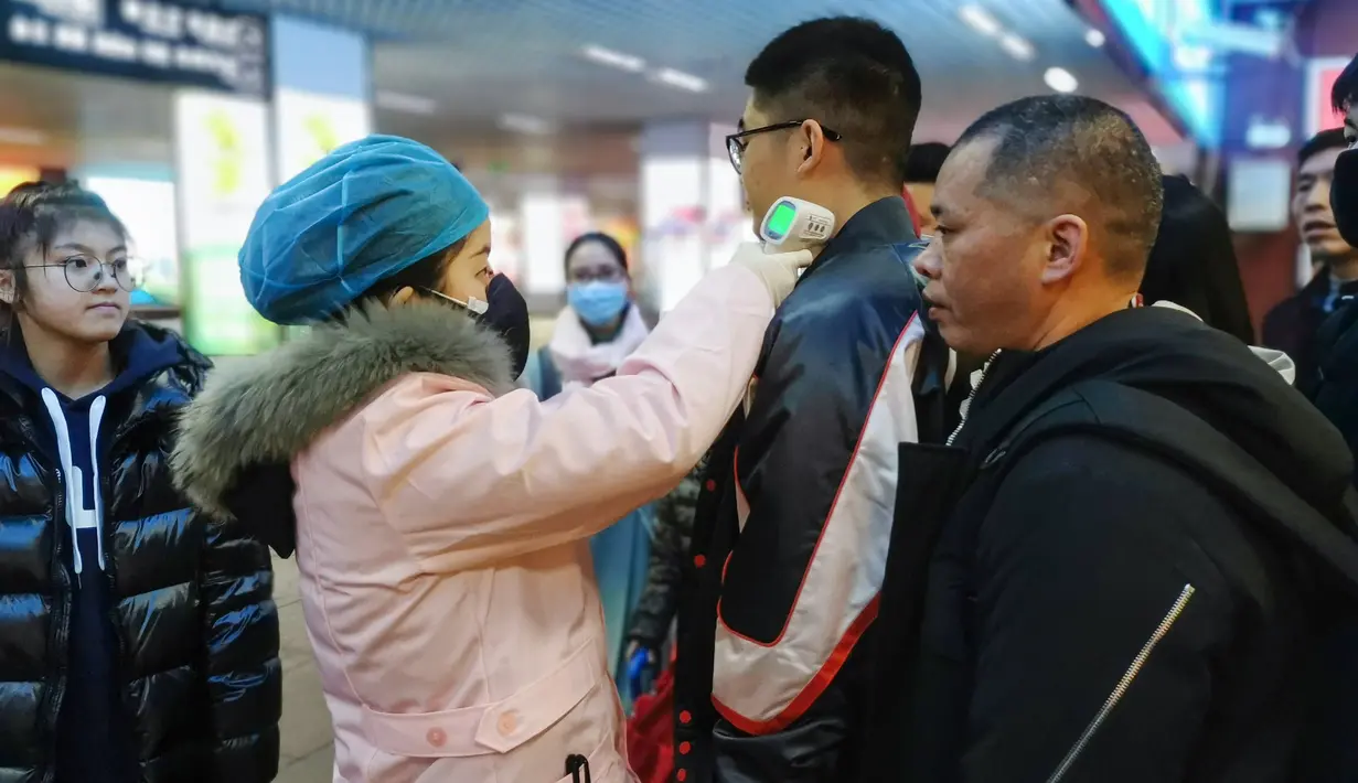 Petugas memeriksa suhu tubuh seorang penumpang di Stasiun Kereta Api Yingtan di Nanchang di Provinsi Jiangxi Tengah, China (22/1/2020). Sebanyak 17 orang meninggal akibat terinfeksi virus corona. (AFP Photo/STR)