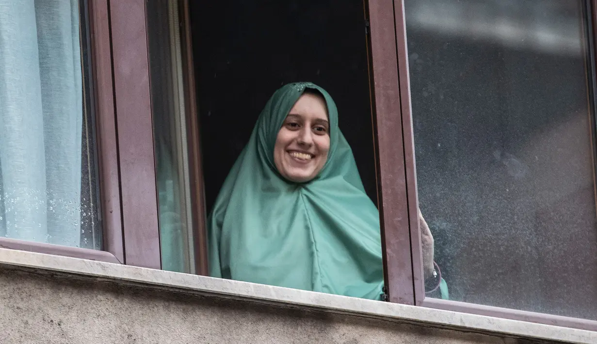 Petugas bantuan Italia bernama Silvia Romano, yang dibebaskan oleh militan Somalia, tersenyum dari jendela setelah tiba di rumahnya di Milan, 11 Mei 2020. Silvia, 25 tahun, memutuskan masuk Islam setelah dirinya diculik dari kota pesisir tenggara Kenya pada November 2018. (AP/Luca Bruno)
