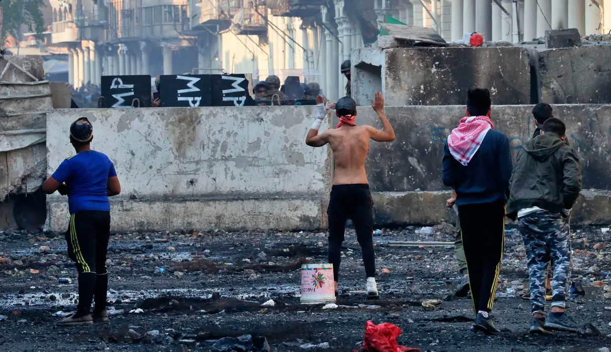 Polisi antihuru-hara meminta para pengunjuk rasa mundur saat bentrokan di Rasheed Street, Baghdad, Irak, Kamis (28/11/2019). Sebanyak 27 demonstran antipemerintah tewas ditembak mati oleh pasukan keamanan Irak dalam sehari. (AP Photo/Khalid Mohammed)