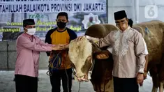 Gubernur DKI Jakarta Anies Baswedan (kanan) menyerahkan sapi kurban di Balai Kota, Jakarta, Jumat (31/7/2020). Pada Hari Raya Idul Adha tahun ini, Anies menyumbangkan sapi kurban jenis limosin seberat 1,3 ton. (Liputan6.com/Immanuel Antonius)