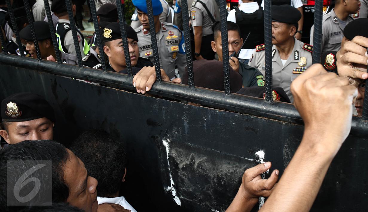 Petugas kepolisian berjaga di pintu masuk Pengadilan Negeri (PN) Jakarta Utara, Selasa (13/12). Ratusan orang membludak berebut masuk ke ruang sidang perdana Basuki Tjahaja Purnama (Ahok) yang berkapasitas maksimal 80 orang. (Liputan6.com/Faizal Fanani)