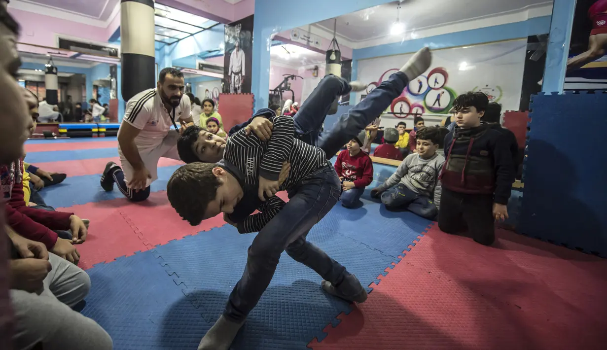 Seorang anak membanting temannya saat latihan di Akademi Olahraga Suriah di Alexandria, Mesir (4/1). Akademi olahraga ini didirkan oleh pengungsi Suriah yang bernama Amir al-Awad. (AFP/Khaled Desouki)