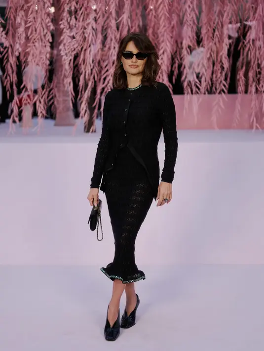 Penelope Cruz tampil serba hitam dengan paduan tweed blazer dan midi skirt. Ia lengkapi busananya dengan hang bag, heels, dan kacamata hitam [Chanel]