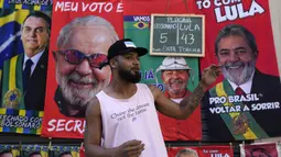 Jose Lucas da Silva berdiri di depan handuk bergambar Presiden Brasil Jair Bolsonaro (kiri) dan mantan Presiden Brasil Luiz Inacio da Silva atau Lula yang dia jual menjelang pemilihan umum presiden di Rio de Janeiro, Brasil, 27 Juli 2022. Ada dua calon yang diunggulkan pada pemilihan umum presiden di Brasil. (AP Photo/Silvia Izquierdo)
