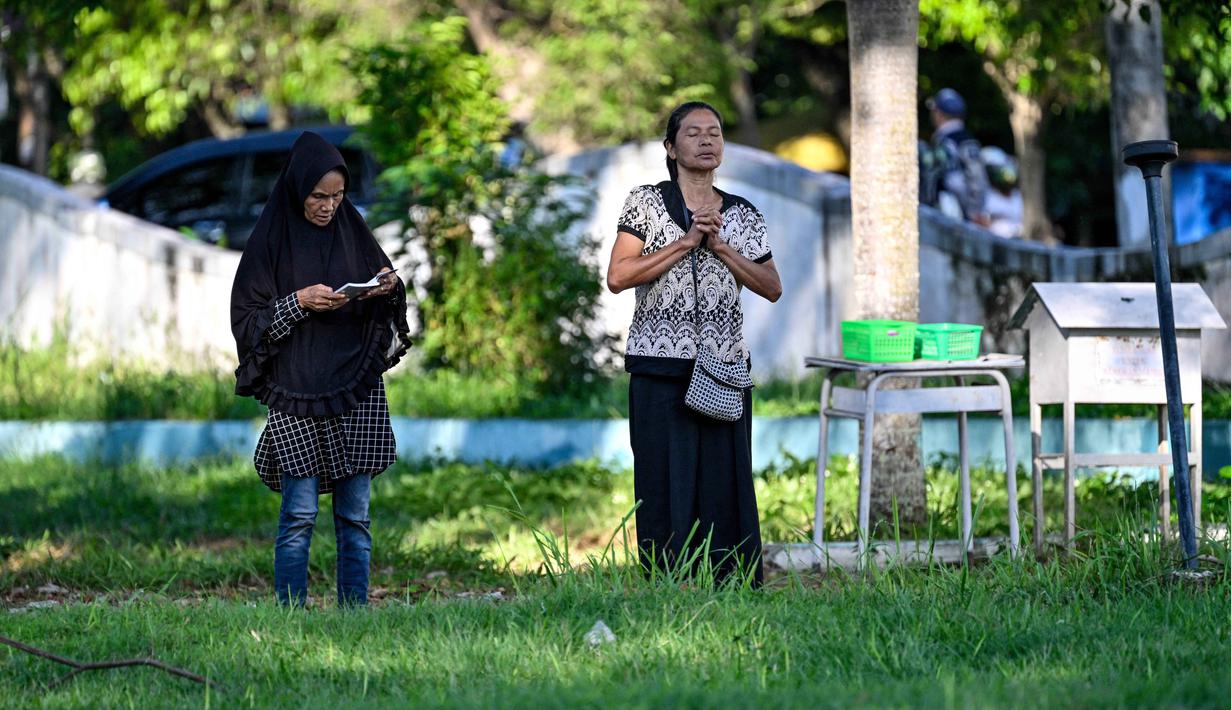 Bencana yang dipicu gempa bumi berkekuatan magnitudo 9,1 itu tercatat sebagai salah satu tragedi paling mematikan dalam sejarah modern. Lebih dari 200 ribu jiwa melayang, ribuan infrastruktur vital hancur lebur, dan roda perekonomian Aceh kala itu nyaris lumpuh total. Tampak dalam foto, orang-orang berdoa untuk kerabat mereka yang kehilangan nyawa dalam peristiwa gempa dan tsunami Aceh pada 2004 lalu di sebuah kuburan massal di Siron, pada 26 Desember 2025. (CHAIDEER MAHYUDDIN/AFP)