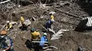 Anggota tim penyelamat mencari di antara puing-puing rumah yang hancur untuk mencari korban atau penyintas setelah tanah longsor saat hujan lebat di Las Tejerias, negara bagian Aragua, Venezuela, pada 10 Oktober 2022. Tanah longsor di Venezuela tengah menewaskan sedikitnya 22 orang dan banyak lagi. dari 50 hilang setelah hujan lebat menyebabkan sungai meluap, Wakil Presiden Delcy Rodriguez mengatakan. (AFP/Yuri Cortez)